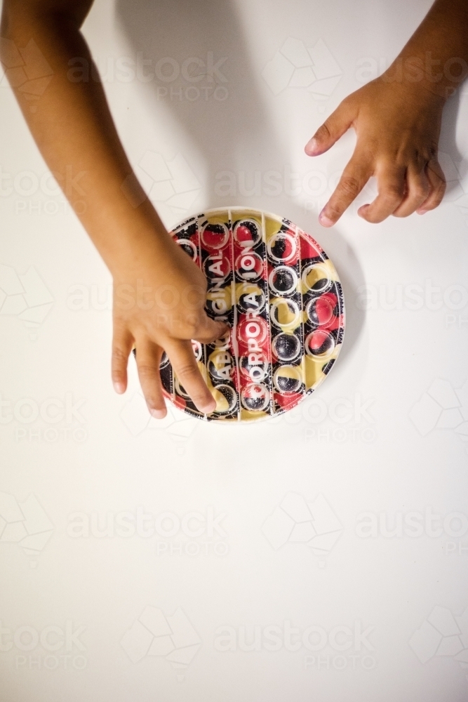 Hands of young Aboriginal child playing with toy - Australian Stock Image