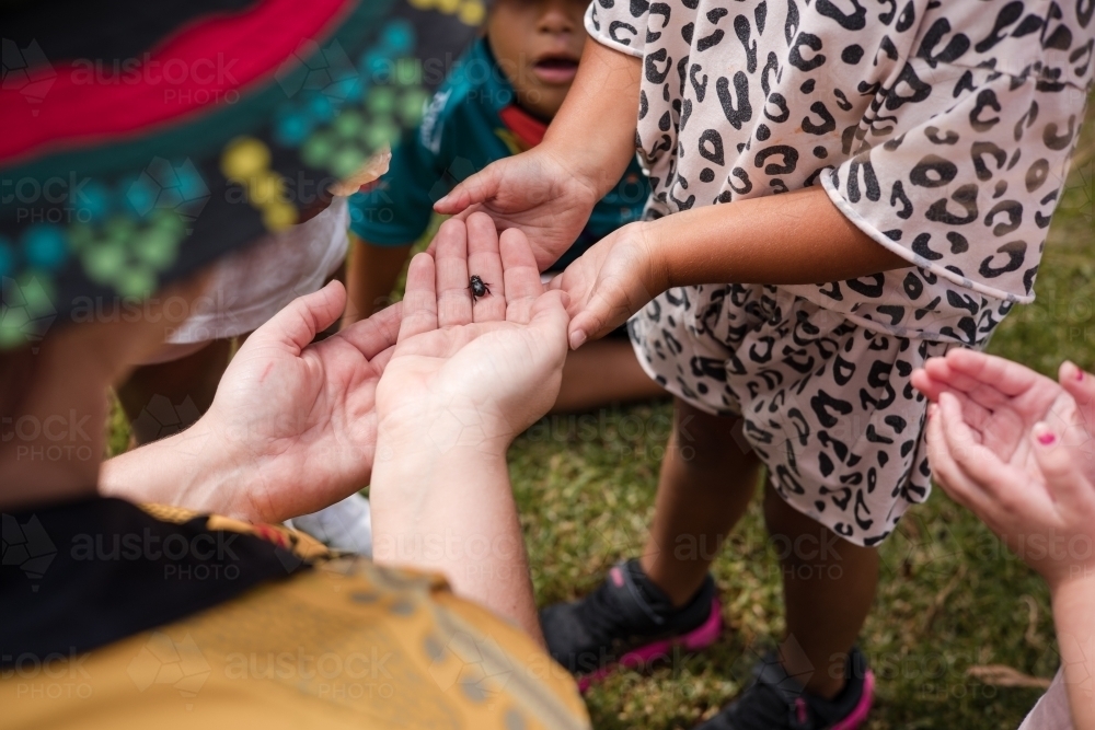 Hands of young Aboriginal girl with teacher at preschool - Australian Stock Image