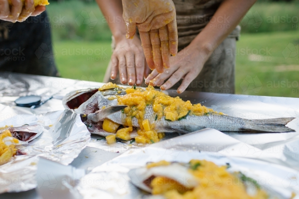 Hands prepping mango fish - Australian Stock Image