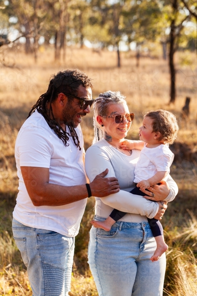 Happy aboriginal Australian family with baby daughter in paddock - Australian Stock Image