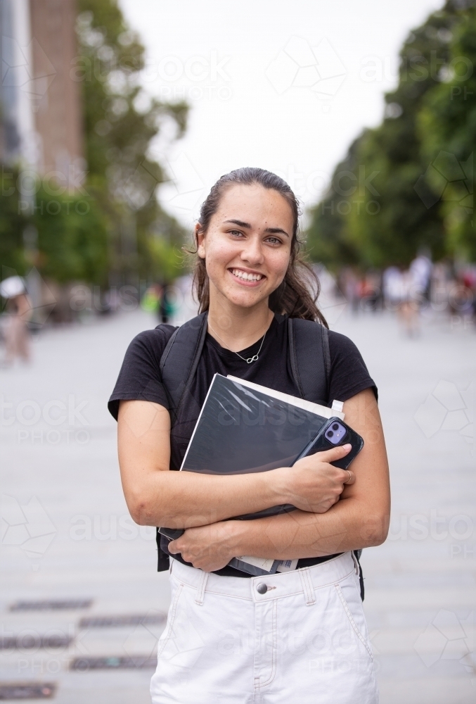 Happy aboriginal female university student holding textbooks  - Australian Stock Image