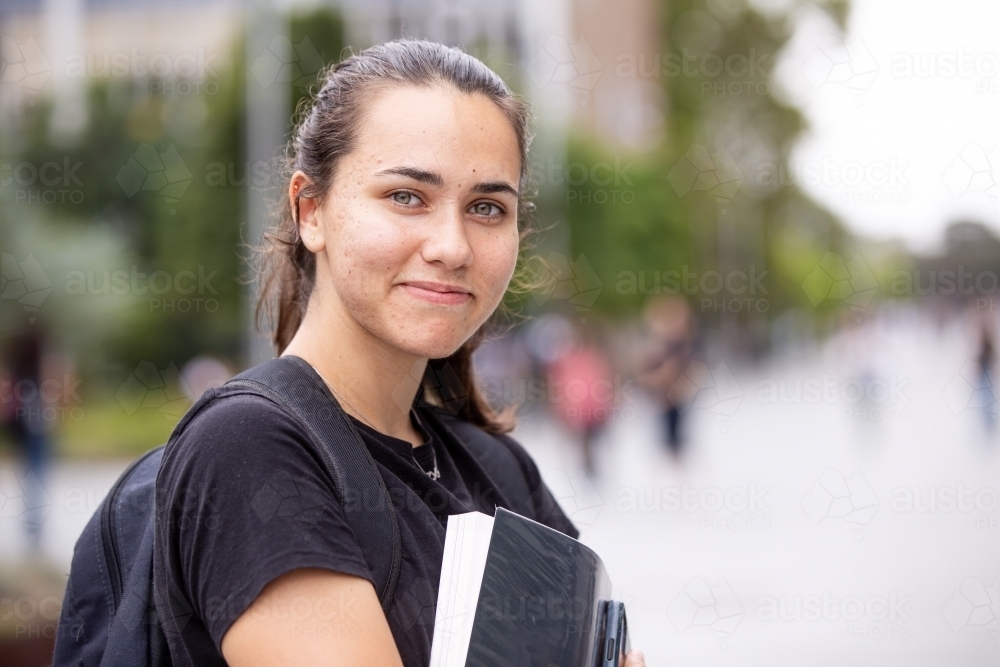 Happy aboriginal female university student holding textbooks  - Australian Stock Image