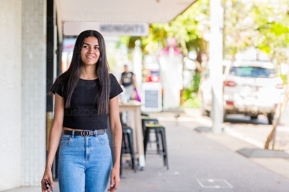 happy aboriginal woman walking in an urban setting - Australian Stock Image