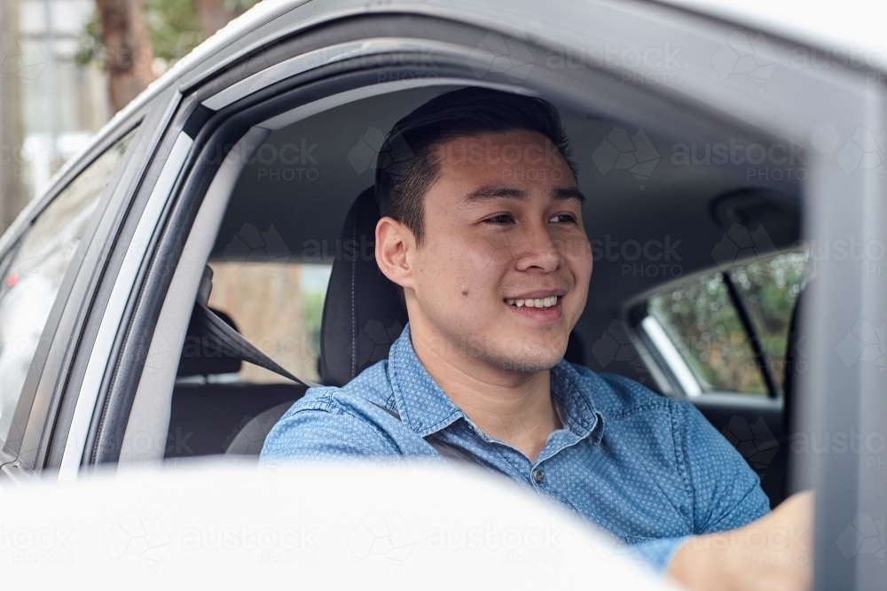 Happy Asian man driving car - Australian Stock Image