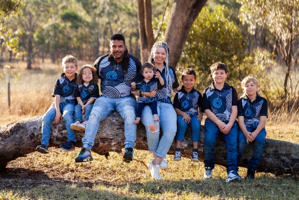 Image of Happy big Australian family sitting together on log - Austockphoto