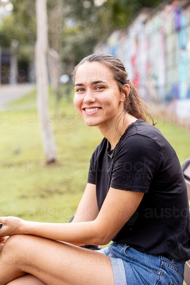 Happy confident young Aboriginal woman looking at the camera and smiling in the park - Australian Stock Image