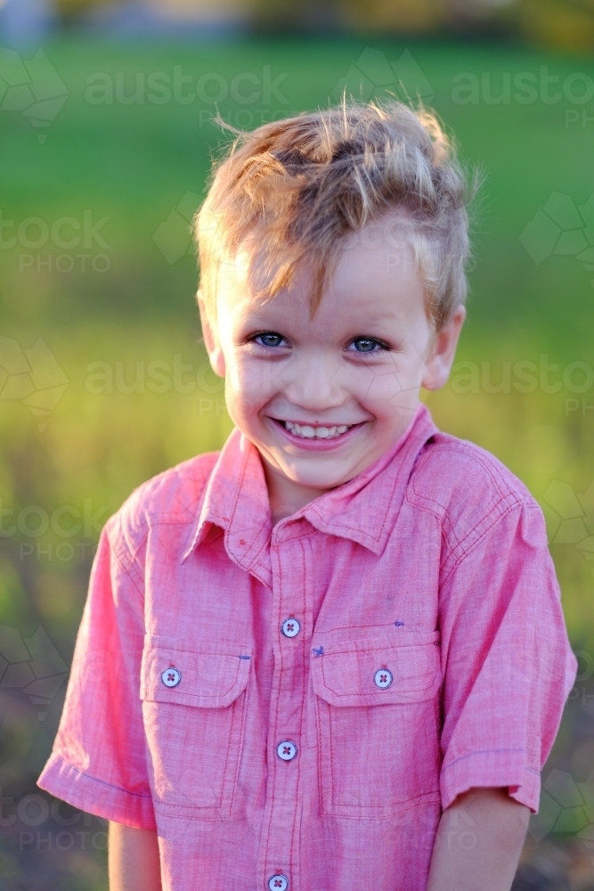 Happy cute smiling boy in a field - Australian Stock Image