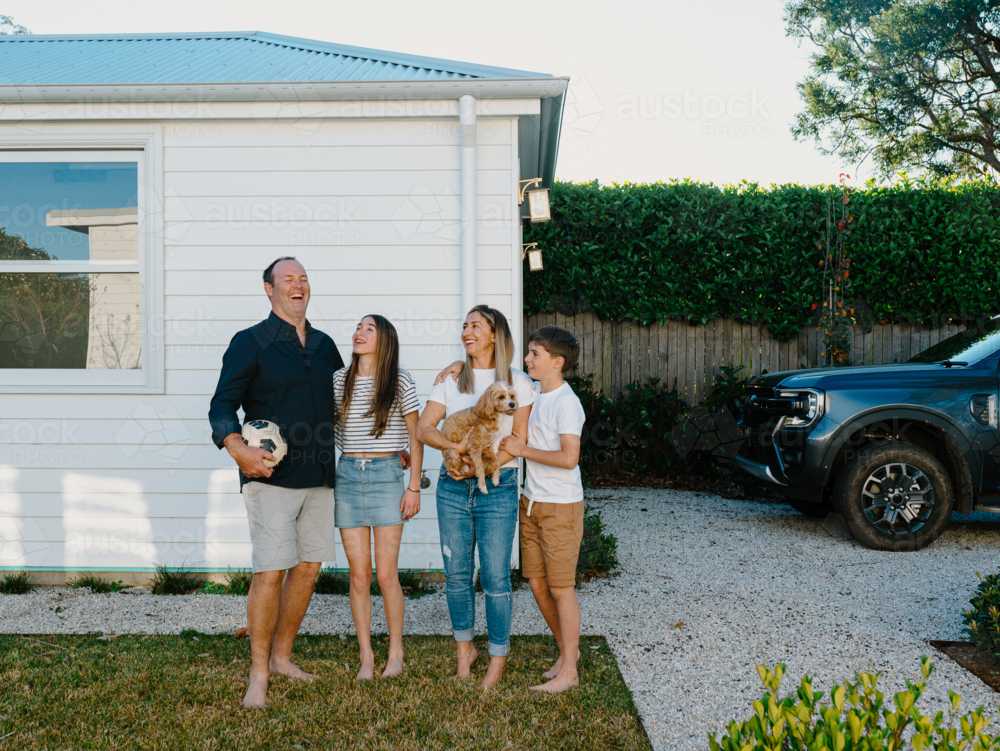 Image of Happy family standing barefoot in their yard. - Austockphoto