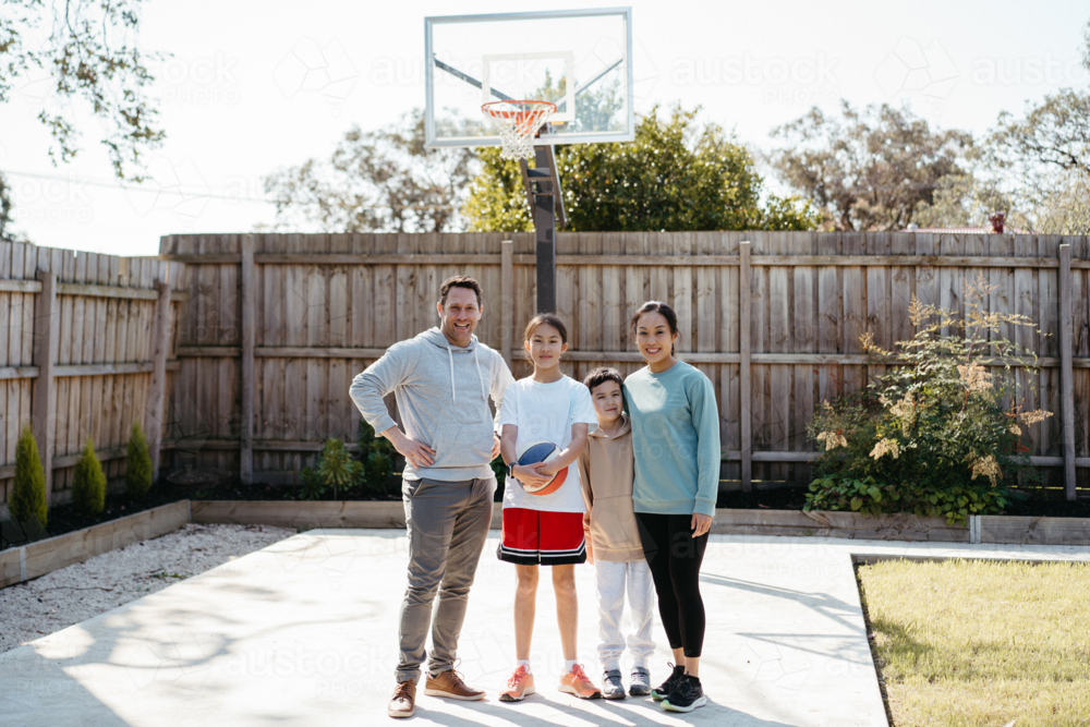 Happy family standing on concrete ground in the yard of their home - Australian Stock Image