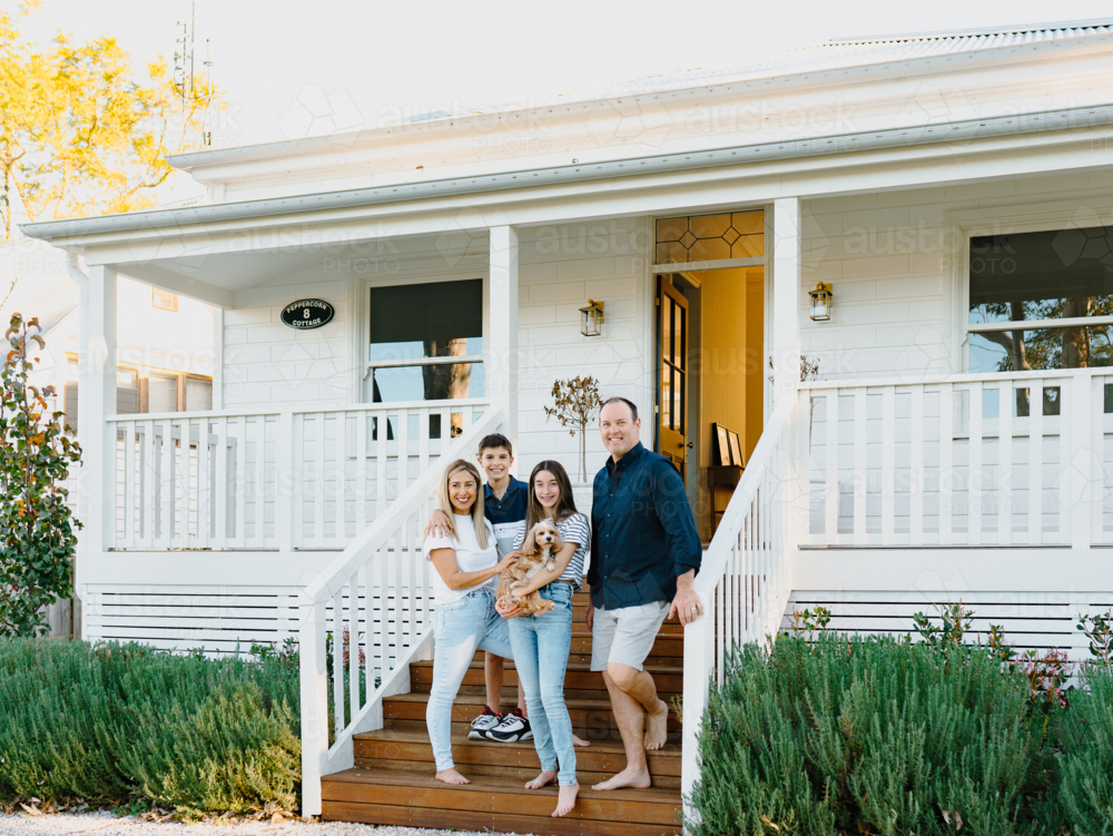 Happy family standing on wooden steps of their porch of Australian home - Australian Stock Image