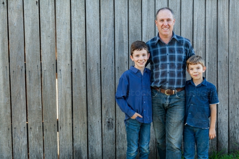 Happy father standing with two young sons - Australian Stock Image