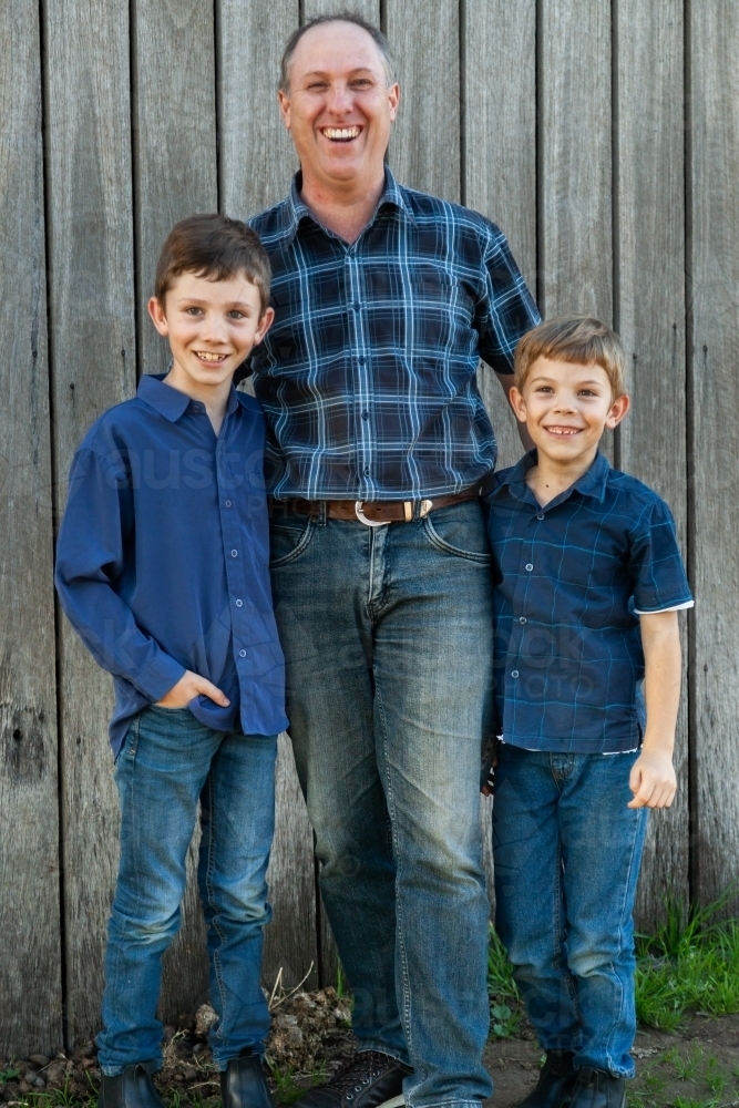 Happy father standing with two young sons - Australian Stock Image