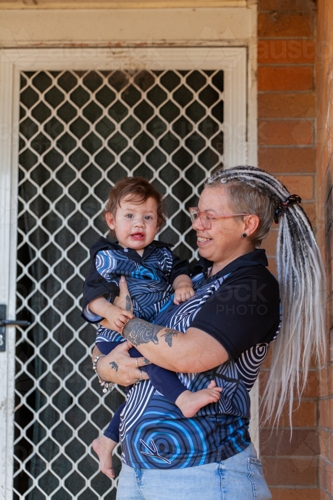 Happy first nations Australian parent with baby girl on front door step - Australian Stock Image