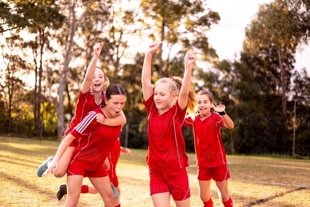 Happy football team of tween girls celebrating together - Australian Stock Image