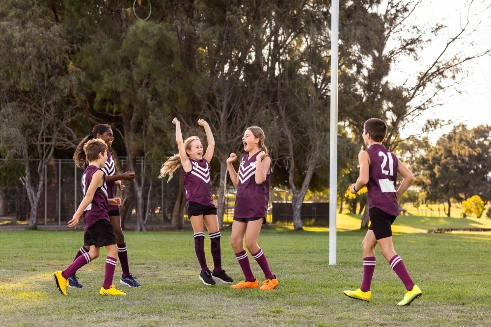 happy kids on football team near goal post - Australian Stock Image