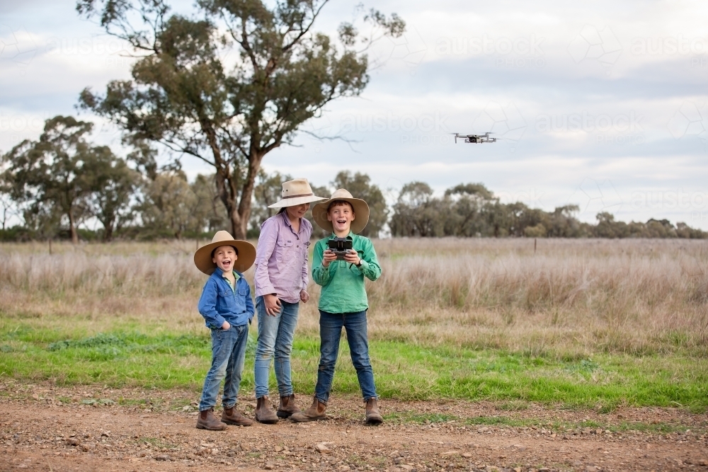 Happy kids using a drone on a farm - Australian Stock Image