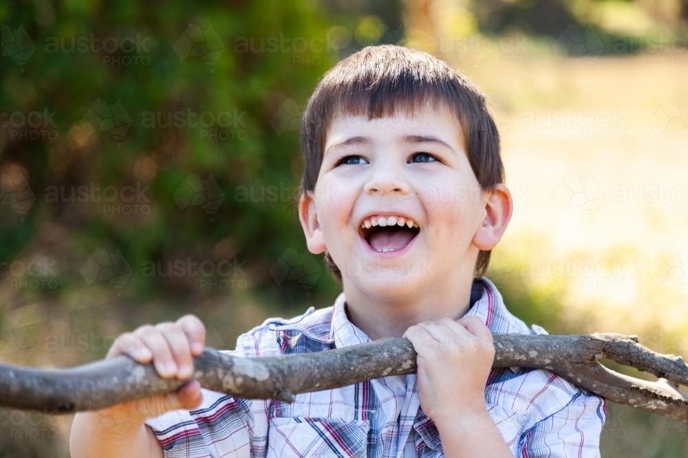 Happy little boy laughing with branch - Australian Stock Image