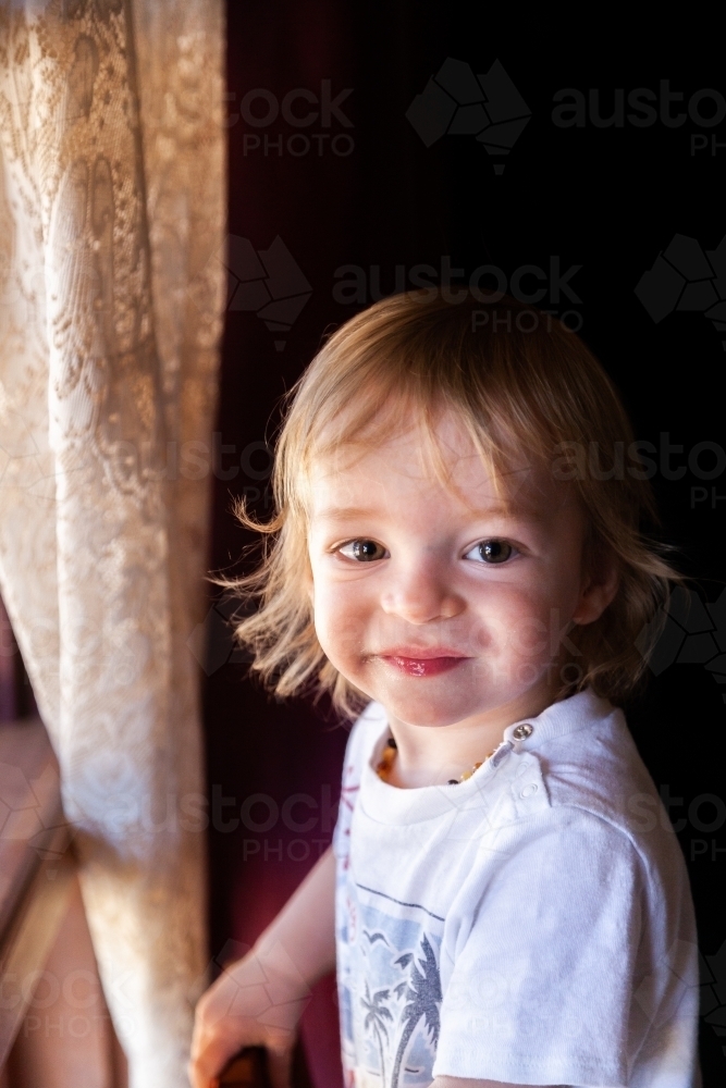 Happy little boy looking out window - Australian Stock Image