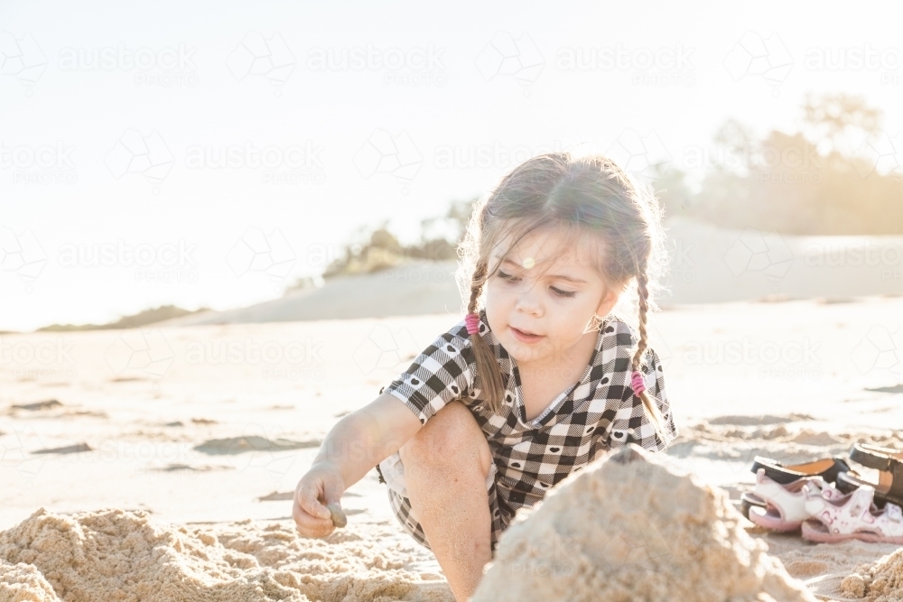 Happy little girl building a sandcastle on beach - Australian Stock Image