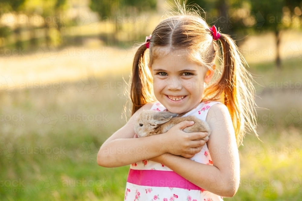 Happy little girl cuddling her pet Easter bunny rabbit - Australian Stock Image