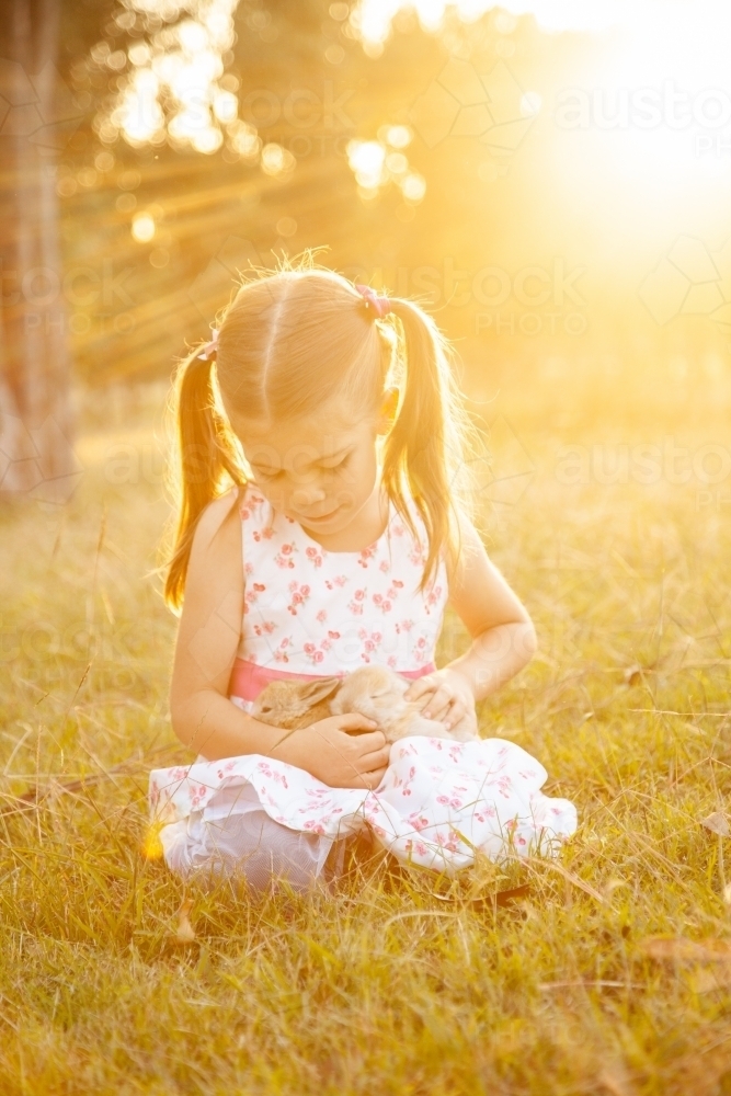 Happy little girl holding an Easter bunny pet rabbit - Australian Stock Image