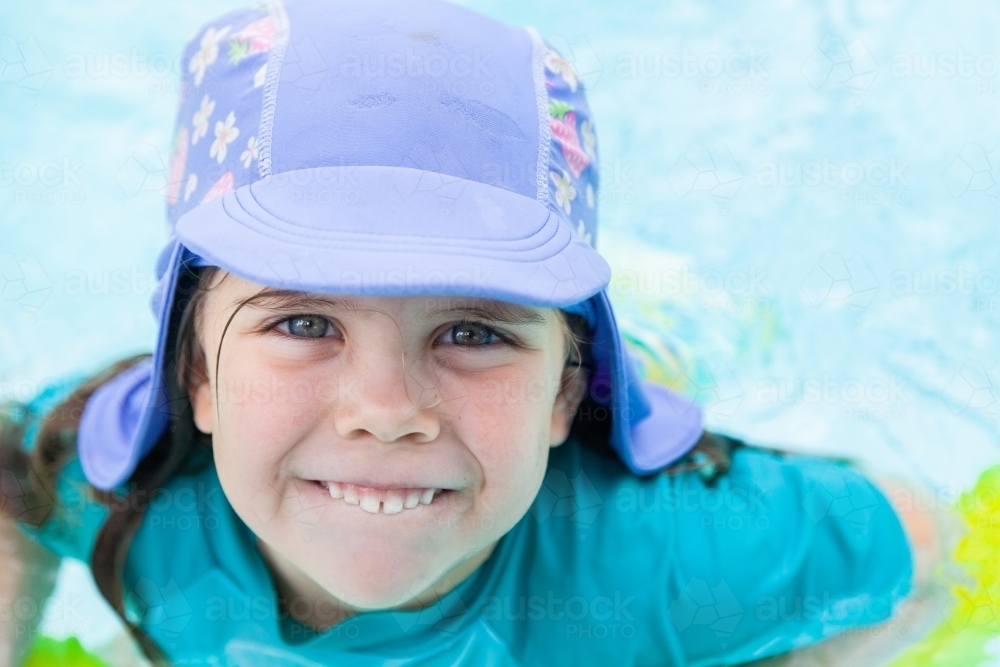 Happy little kid with swimming hat smiling in pool in summer - Australian Stock Image