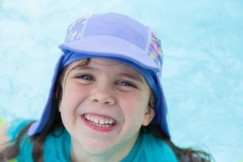 Happy little kid with swimming hat smiling in pool in summer - Australian Stock Image