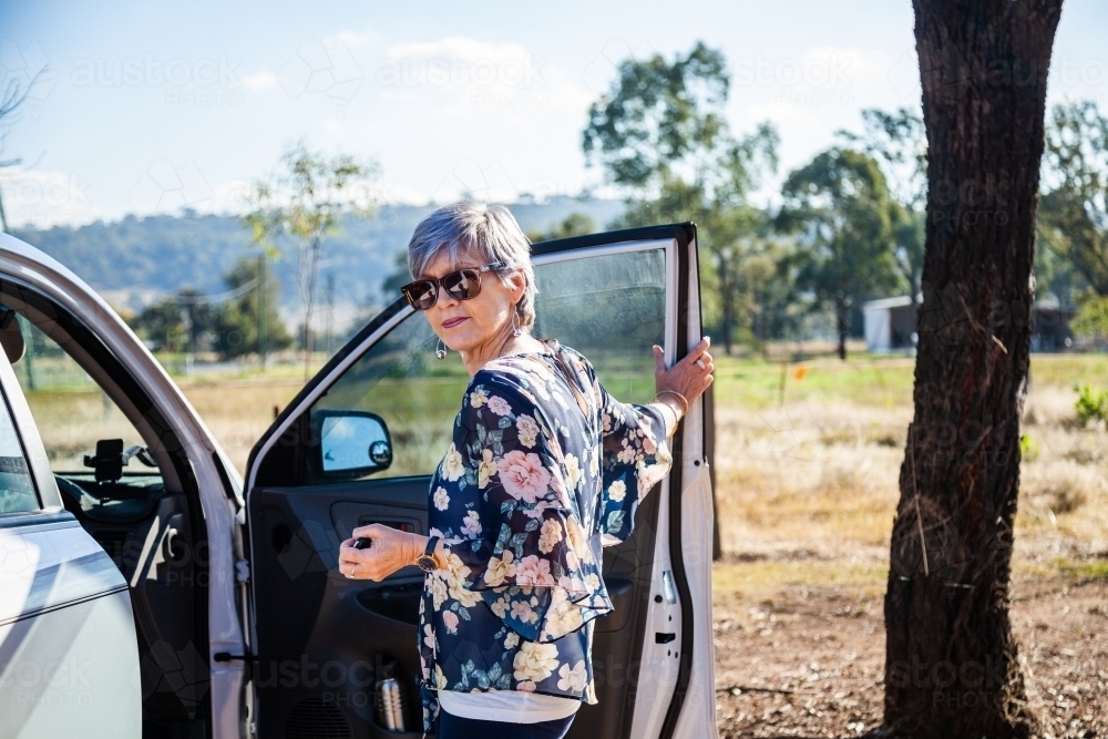 Happy mature aged woman getting into her car - Australian Stock Image