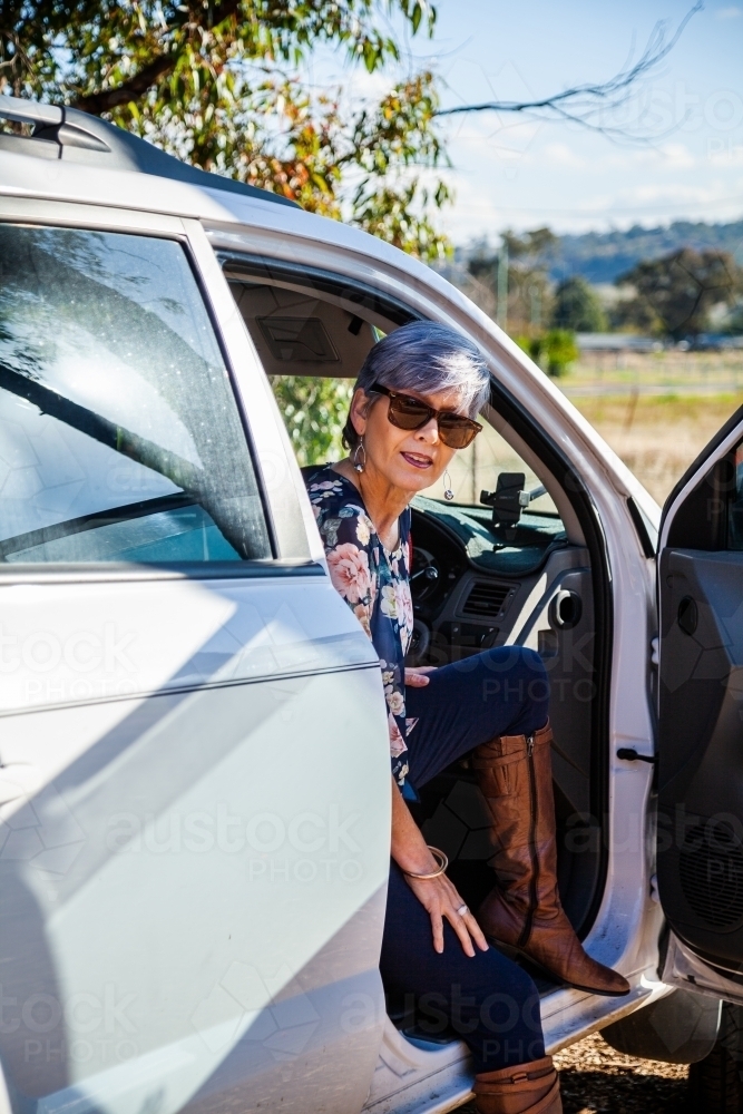 Happy mature aged woman getting into her car - Australian Stock Image