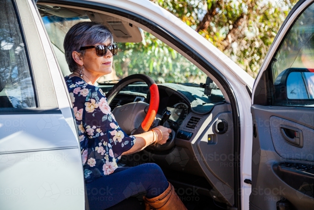 Happy mature aged woman getting into her car - Australian Stock Image