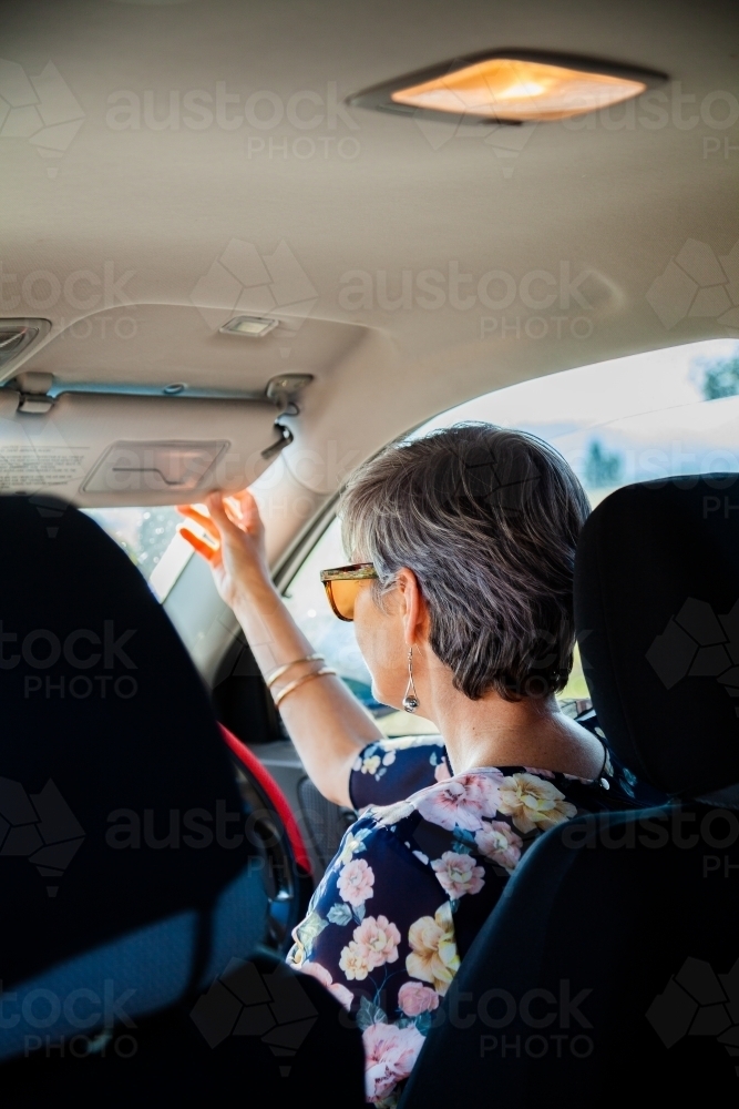 Happy mature aged woman getting into her car - Australian Stock Image