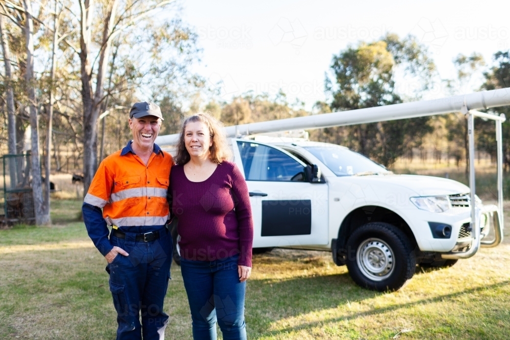 happy middle age couple standing together in front of tradie work ute - Australian Stock Image