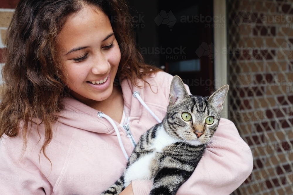 Happy multicultural teen holding cat - Australian Stock Image