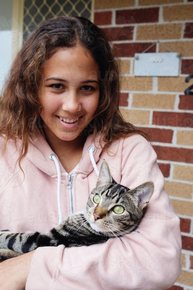 Happy multicultural teen holding cat - Australian Stock Image