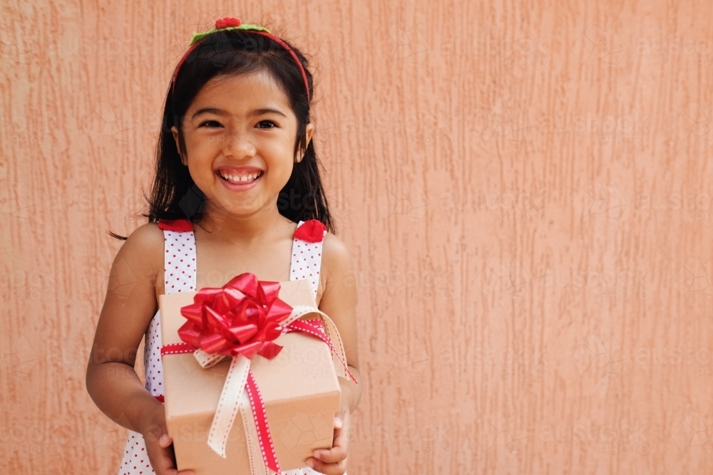 Happy multicultural young girl holding present box - Australian Stock Image