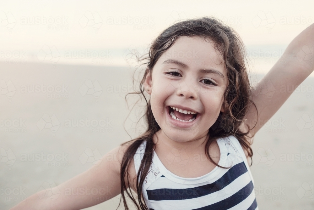 Happy multicultural young little girl on the beach - Australian Stock Image