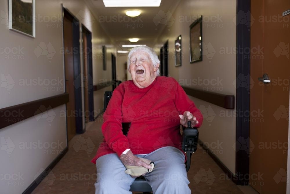 Happy nursing home resident sitting in wheelchair - Australian Stock Image