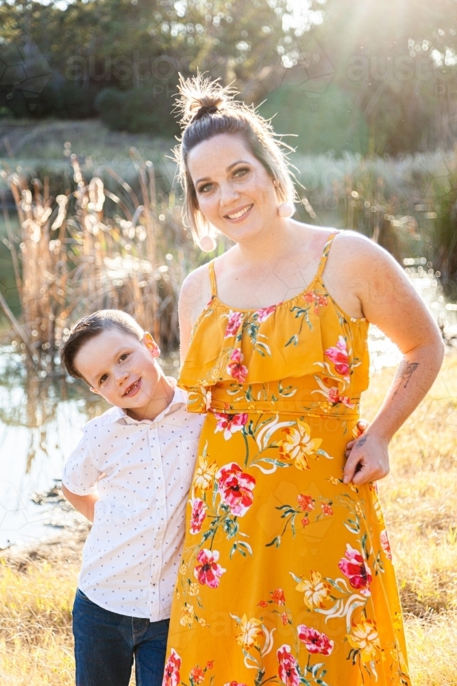 Happy parent standing with her son outside near dam - Australian Stock Image
