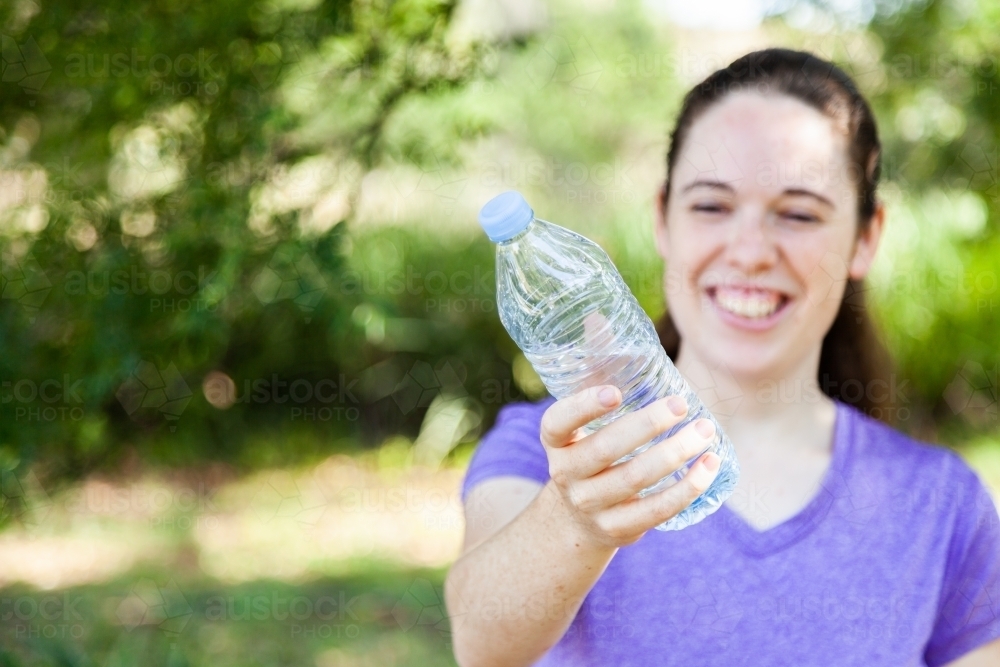 Happy person holding plastic water bottle outside - Australian Stock Image