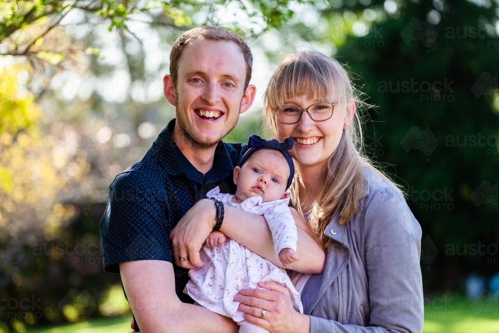 Happy portrait of young family outside in garden - Australian Stock Image