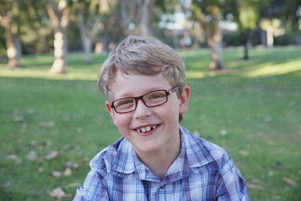 Happy preteen boy wearing glasses in the park - Australian Stock Image