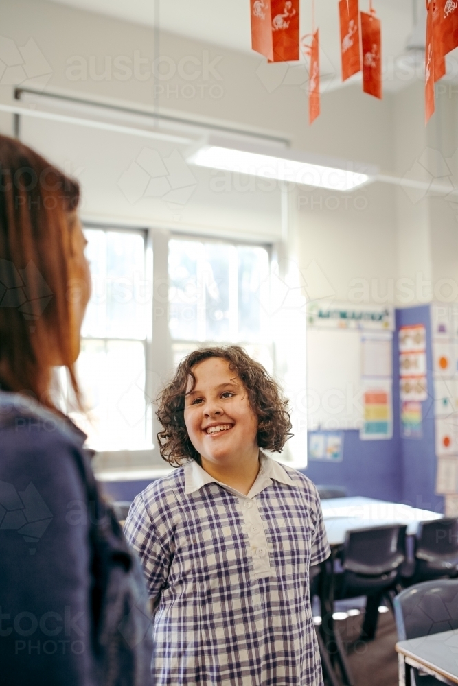 Happy primary school student in classroom with teacher - Australian Stock Image