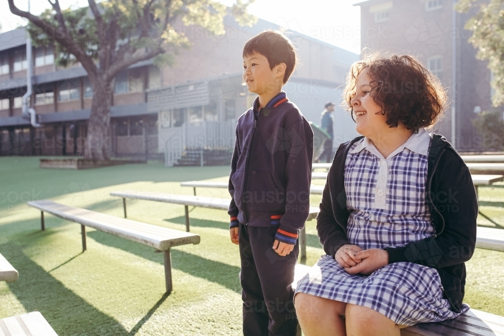 Happy primary school students on bench seats - Australian Stock Image