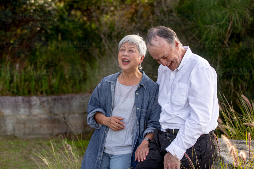 Happy senior couple laughing together outdoors in nature - Australian Stock Image