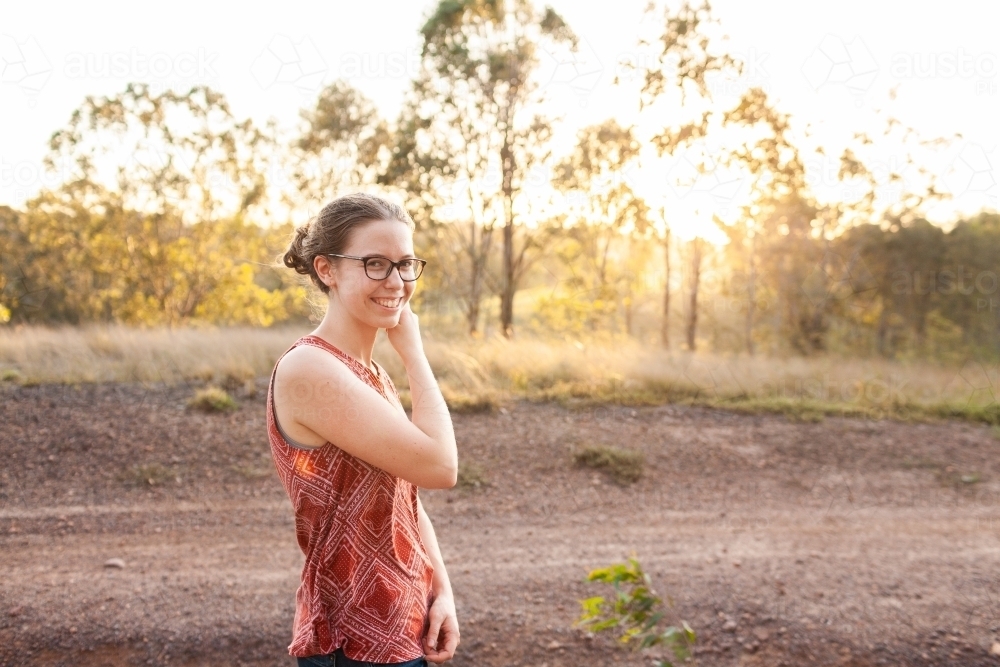 Happy smiling young person standing outside on summer evening - Australian Stock Image