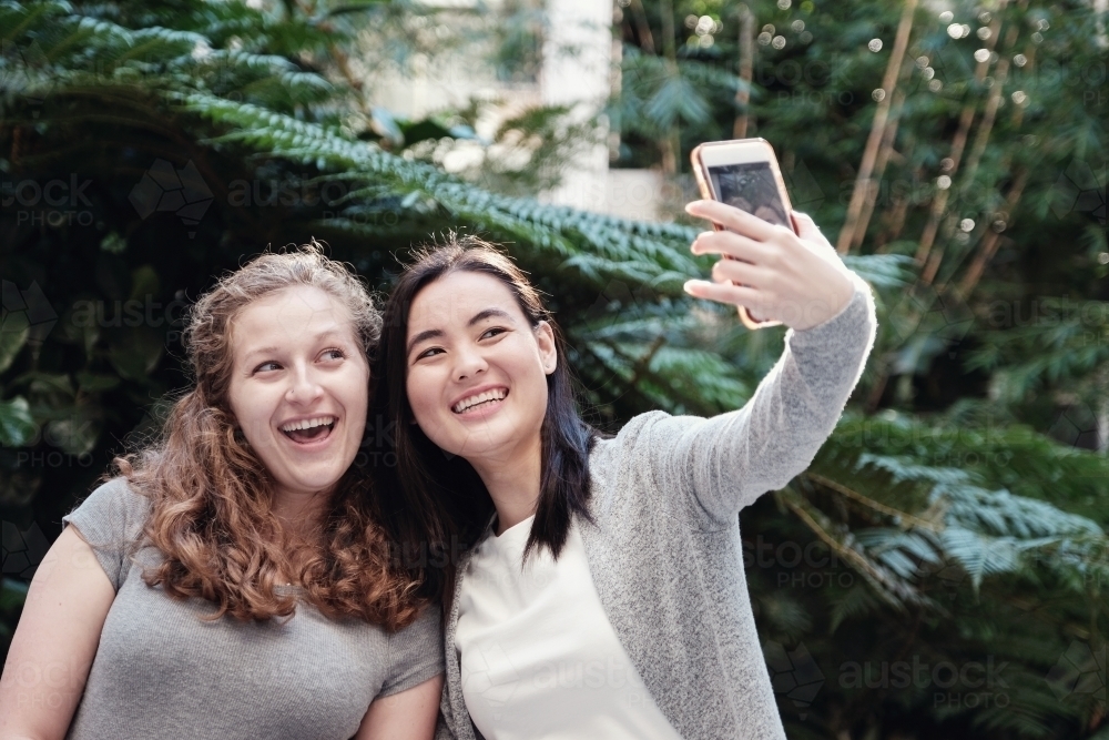 Happy students girl friends using mobile - Australian Stock Image