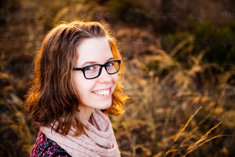 Happy teen girl smiling in golden sunset light outside - Australian Stock Image