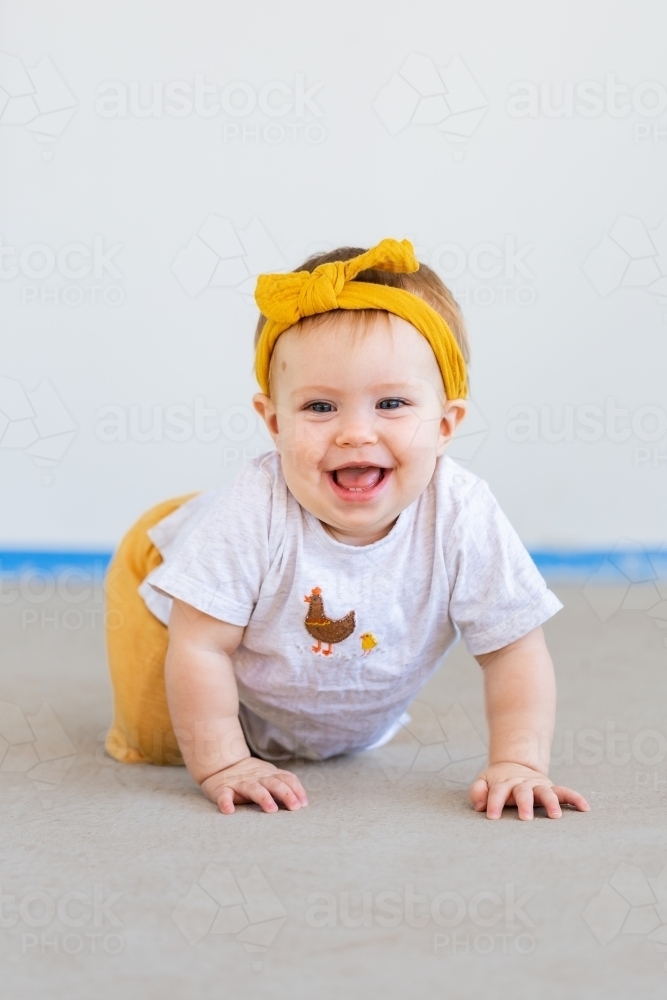 happy ten month old baby crawling and smiling - Australian Stock Image