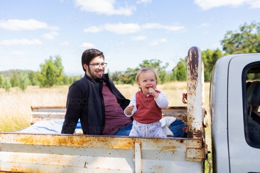 Happy toddler country kid with dad in back of ute on australian farm - Australian Stock Image