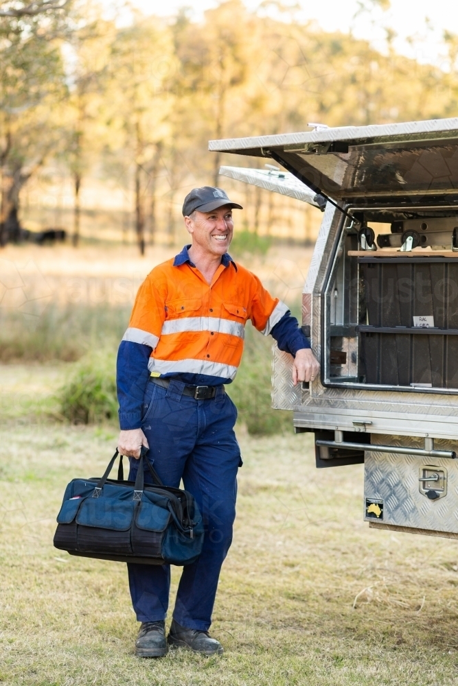 Happy tradie leaning on back of his work ute - Australian Stock Image